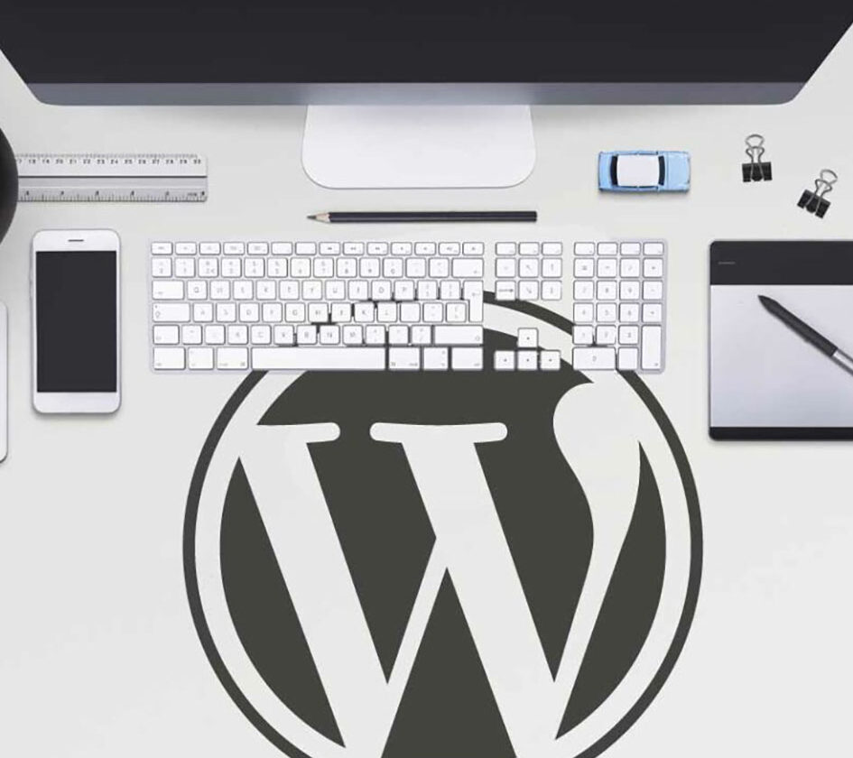 Wordpress logo on computer desk surrounded by keyboard and screen