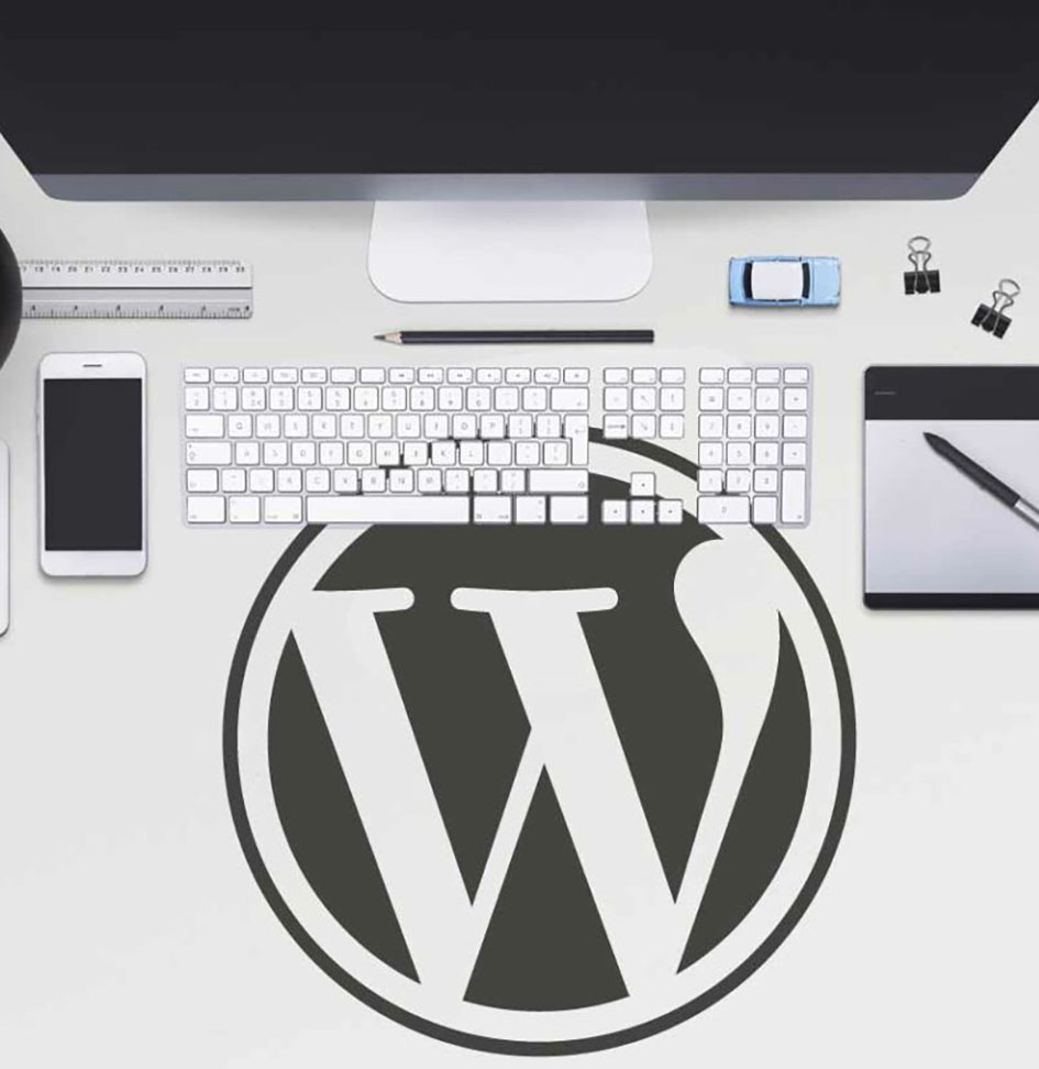 Wordpress logo on computer desk surrounded by keyboard and screen